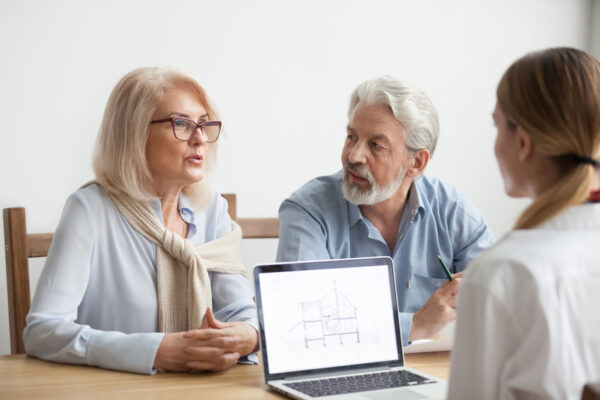 Un couple de retraité senior échangeant avec une conseillère en immobilier
