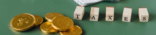 Taxes and levies in France represented by coins and wooden letters: a symbol of the tax system for foreign freelancers.